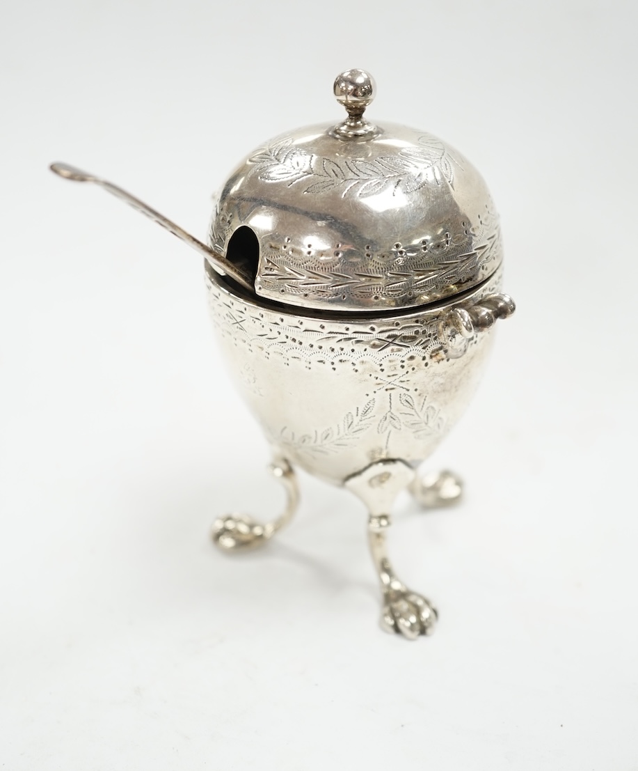 A Victorian silver egg shaped mustard pot, on paw feet, London, 1867, 10.5cm, with an earlier silver mustard ladle. Condition - fair